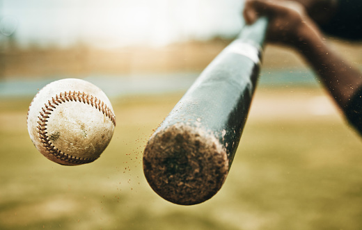 Baseball hit, sports and athlete on a outdoor field hitting a ball in a game with a baseball bat. Sport, baseball player and man busy with exercise, fitness and workout training on green grass