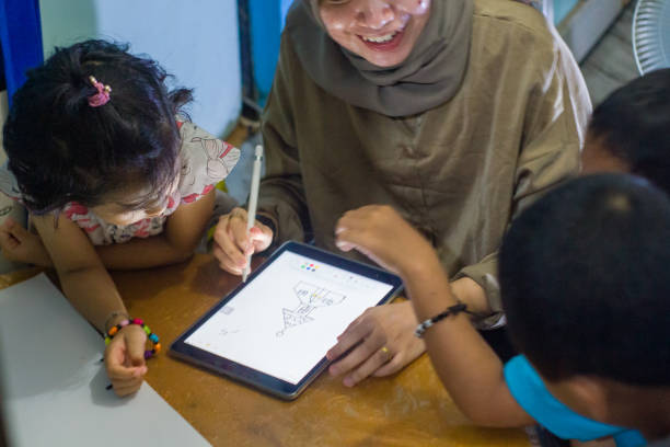 istock younger siblings learn to use ipad with older sister at home 1446310901