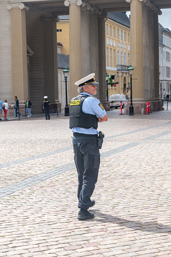 Copenhagen, Denmark - July 26, 2022: Police officer secure Danish Royal Guard during changing of the guard at Amalienborg Square.