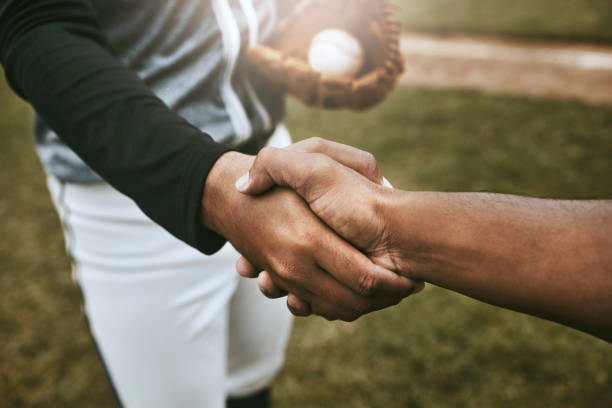 os jogadores de beisebol apertam a mão antes do jogo no campo de beisebol para boa sorte, acordo e apoio. esportes, fitness e atletas apertando as mãos para mostrar união, votos de felicidades e esperança de sucesso durante a partida - baseball baseballs sport close up - fotografias e filmes do acervo