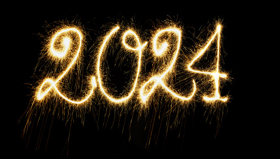 Sparkling  Year 2024 painted with sparkles. Written on a deep black background.