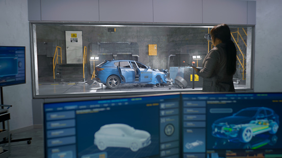 Engineer in experimental crash test laboratory watching process of traffic accident simulation, to get safety parameters of a new electro eco-friendly car body using computer system.