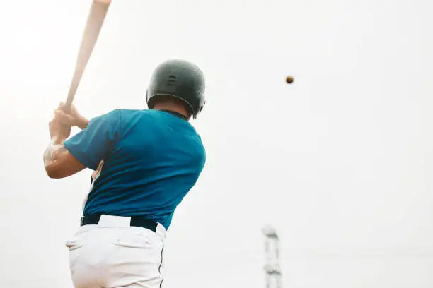 Photo of Baseball player, bat and homerun with sky and baseball for sports, game or contest outdoor in summer. Man, sport and hit in sunshine at stadium, arena or field in competition, match or training