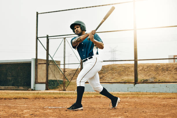 baseball man, stadium game or hit ball with bat on a sport field in a game. sports player with practice, strike and concentration to win match by competitive male batter focus during training outdoor - baseball bat fotos imagens e fotografias de stock