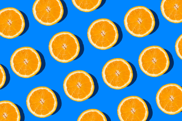 istock Summer flat lay pattern made with fresh orange fruit slices on vibrant blue background. Minimal sunlight concept with sharp shadows. 1446321957