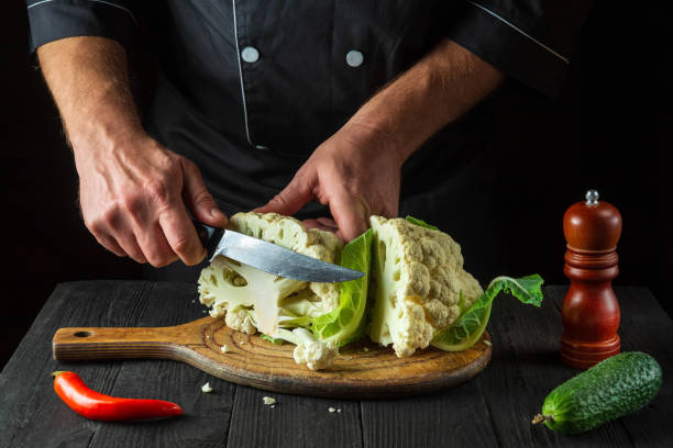 o chef está cortando couve-flor em uma cozinha de restaurante. a ideia de uma deliciosa dieta para o café da manhã ou jantar. - hotel commercial kitchen organic salad - fotografias e filmes do acervo