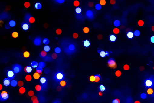 Textured festive dark background with blurred red-blue lights. Background for holiday design. New year, Christmas. Selective focus, defocus