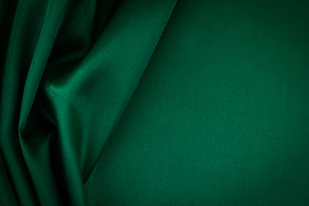 Abstract monochrome elegant luxury cloth background. Green color background with drapery and wavy folds of luxurious silk satin material. Top view stock photo