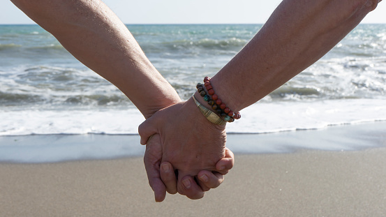 gay couple holding hands by the sea
