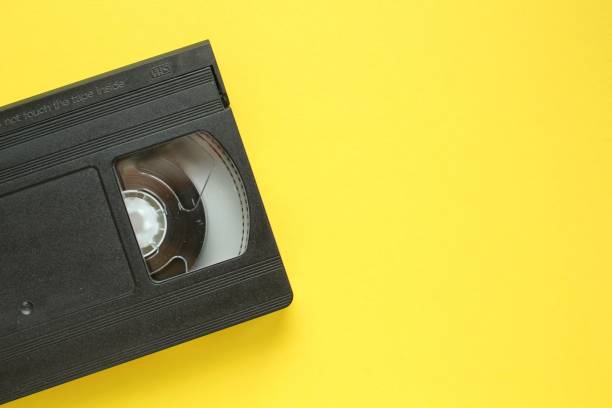 istock Black VHS videotape recorder cassette on yellow background. Old obsolete technology for tape recording and watching media movies 1446334558