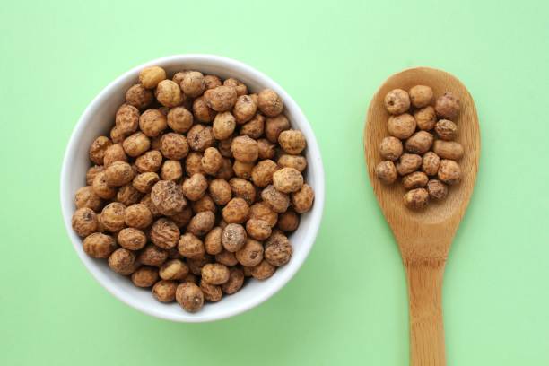 chufa, tigernut, earth almond on white ceramic bowl and wooden spoon on green background. healthy vegan food concept. - healthy eating food and drink nutrition label food imagens e fotografias de stock