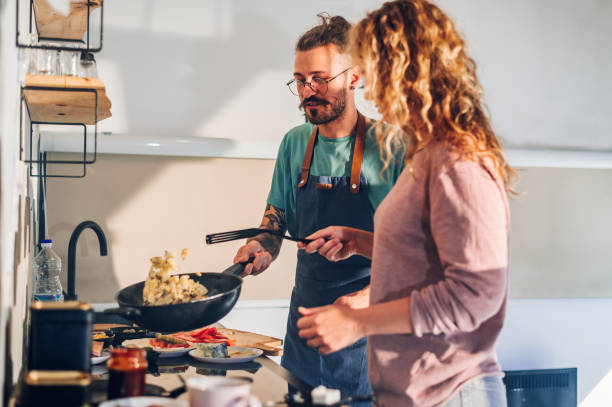istock Young couple making breakfast together in the kitchen at home 1446336107