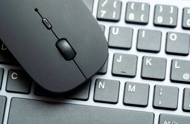 Modern flat office PC mouse laying on a computer keyboard, two objects closeup, nobody, detail. IT job tools, work place symbol concept, nobody. Minimal workspace, PC equipment and office accessories