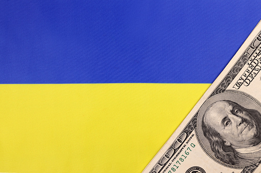 Ukrainian flag and American money dollars. The concept of lend lease, war in Ukraine, financial international donations, aid, support for countries