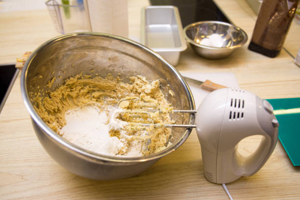 electric hand mixer kneads dough in a deep metal bowl electric hand mixer kneads dough in a deep metal bowl electric whisk stock pictures, royalty-free photos & images