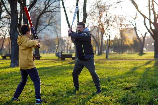 A father teaches his son to use a baseball bat.