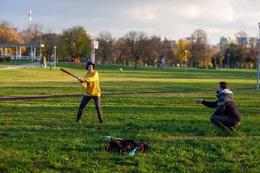 A Handsome dad with his little cute sun are playing baseball on green grassy lawn