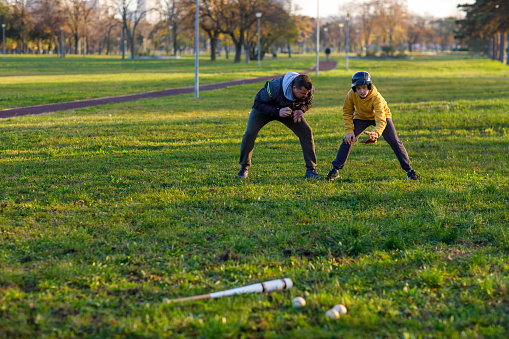 Father plays baseball together with his son at park.
