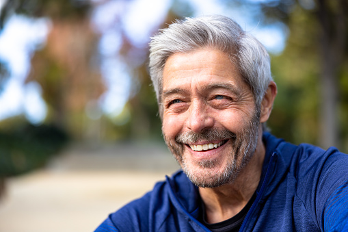 A senior man smiling outdoors at a workout