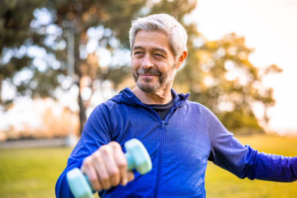 Senior man working out outside with weights stock photo