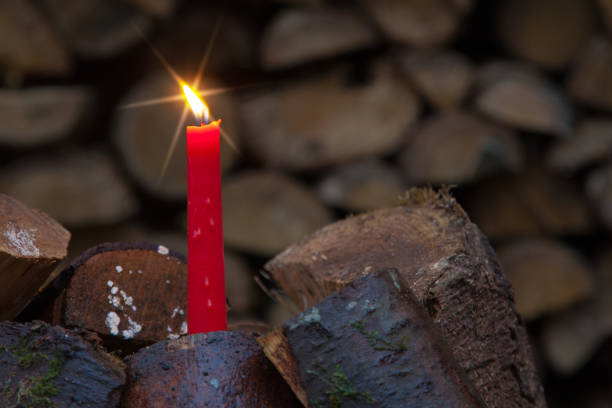 Candlelight with a light star in a stack of wood, the unusual Christmas motif for forestry.