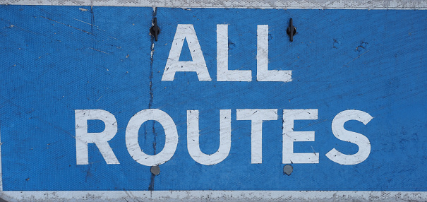 all routes direction sign in white over blue background