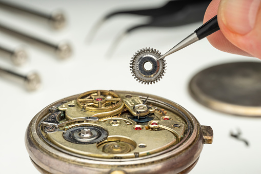 WATCHMAKER REPAIRING A POCKET WATCH IN THE WORKSHOP. CLOSE UP.