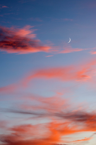 New moon at sunset where the clouds are various shades of red.