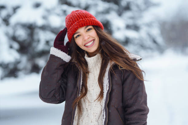 Beautiful Young Smiling woman  in her Winter Warm Clothing walking in the snow forest. stock photo