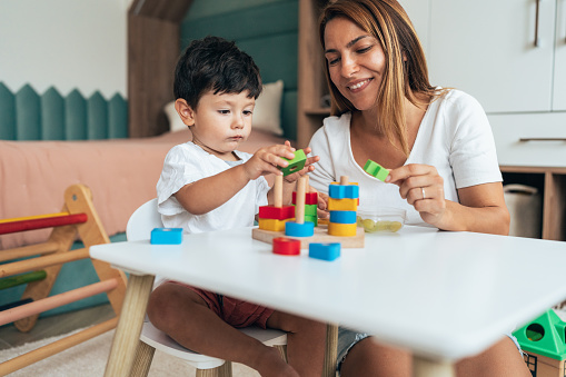 Mother and son playing at child's room. Playing and bonding at home. Mom and toddler have fun