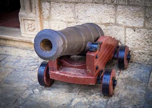 An old cannon standing in front of the entrance to the building