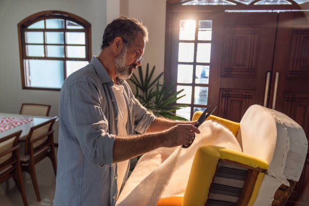 Portrait of an elderly man upholstering a armchair in his living room