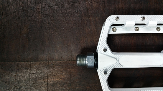 close-up white aluminum Flat Pedal with interchangeable spikes on a dark wooden background top view