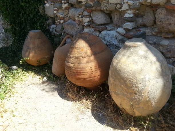 istock Ancient pottery vessels upside down on ground against stony wall 1446368239