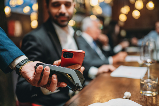 Un hombre está pagando la cuenta en el restaurante usando su teléfono inteligente photo