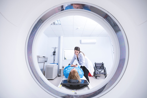 Cancer treatment in a modern medical private clinic or hospital with a linear accelerator. Professional doctors team working while the woman is undergoing radiation therapy for cancer