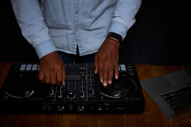 Black man DJ works with a mixer and laptop.