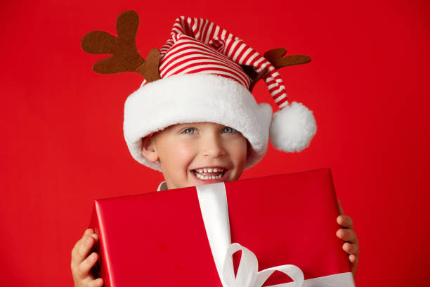 istock Charming smiling boy in Santa's Christmas cap with gift 1446384063