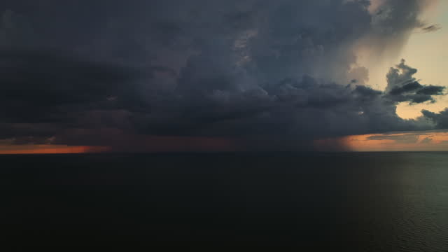Dark stormy clouds forming on gloomy sky during heavy rainfall season over sea surface in evening