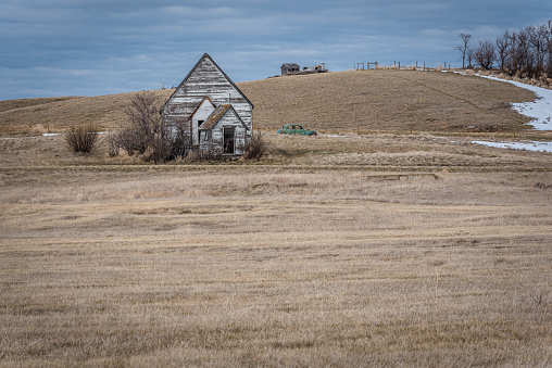 Neidpath, Saskatchewan’s old, abandoned white church with a classic, abandoned car on a snowy hillside