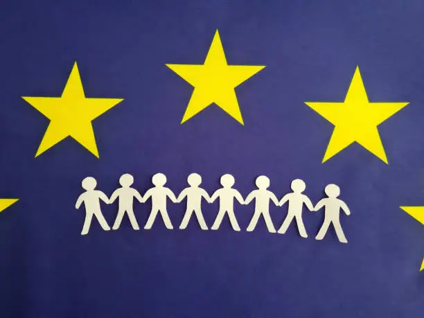 Photo of European Union citizenship concept. Many paper figures holding hands stand