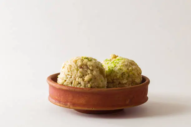 Photo of moa, popular bengali dessert is served on a clay plate. this is made of jaggery, puffed rice and made into a ball. famous sweet food in winter season.