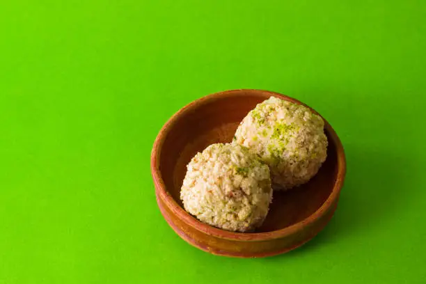Photo of moa, popular bengali dessert is served on a clay plate. this is made of jaggery, puffed rice and made into a ball. famous sweet food in winter season.