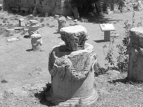 A grayscale shot of ancient ruins, pieces of historic pillars in Gereion Temple in Greece
