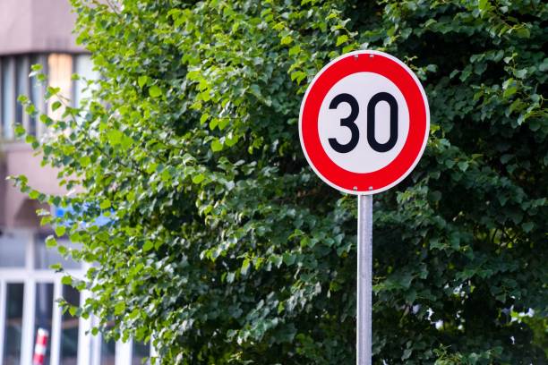 istock Red and white 30 speed limit sign with lush green tree in the background 1446407189