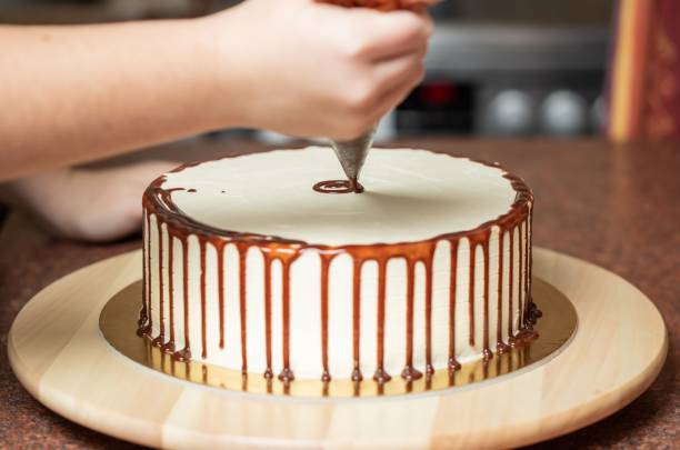istock Young woman decorating a freshly baked cake in her kitchen 1446407423