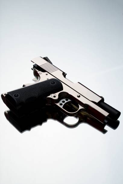 istock Vertical closeup of an isolated silver compact handgun on a white background 1446408315