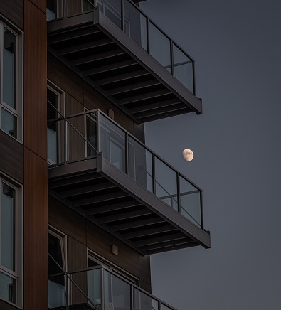 A closeup of luxury residential balconies on a building with a moon on the background at night