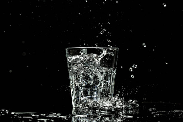 spruzzi e gocce d'acqua in un bicchiere sono isolati su uno sfondo nero. posizione per il testo - martini brand vermouth foto e immagini stock