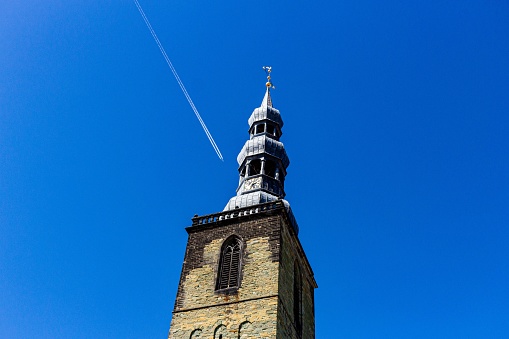 Stainless Steel cross on church steeple isolated on blue sky background.